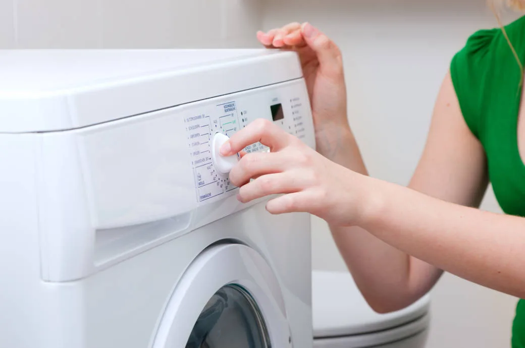 Woman washing clothes with machine - SMS Appliances